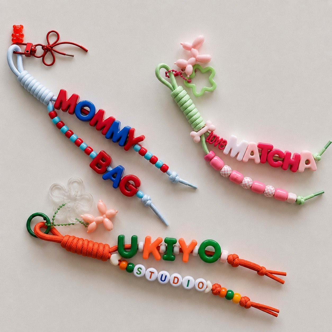 Colorful handmade charm bar keychains spelling Mommy Bag, Love Hateha, and Ukiyo Studio